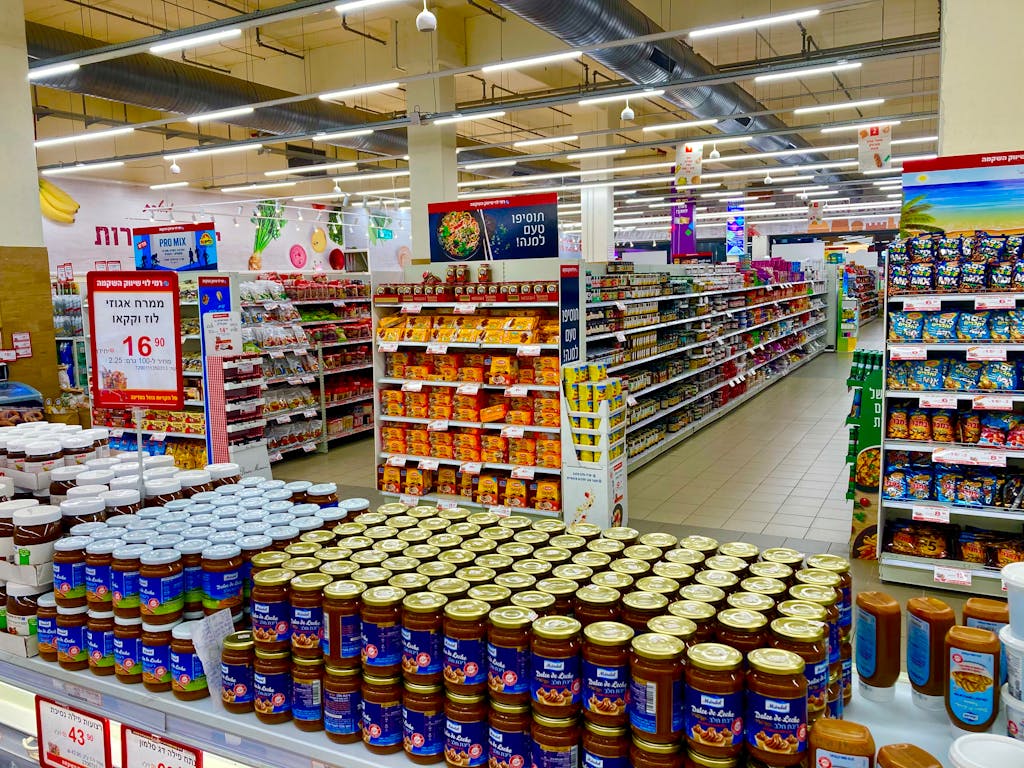 Wide view of a fully stocked supermarket aisle with jars and various products on shelves.
